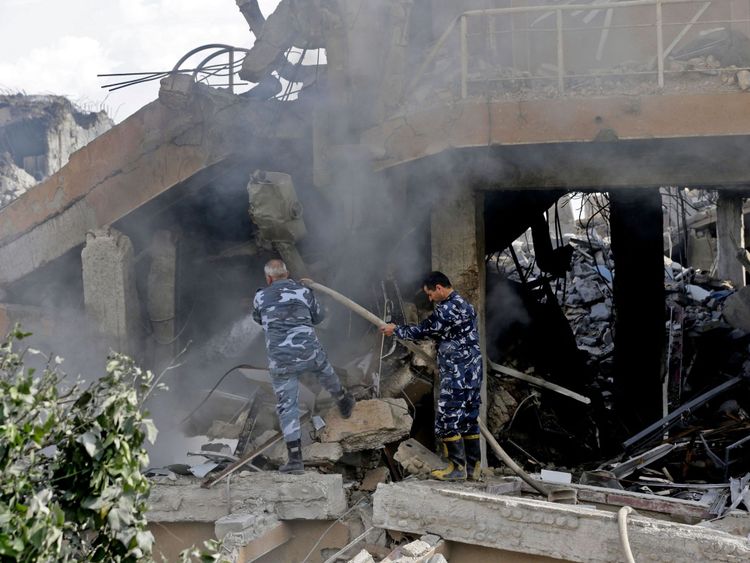 Syrian soldiers extinguish a fire in the wreckage of the part of the Scientific Studies and Research Centre in Damascus
